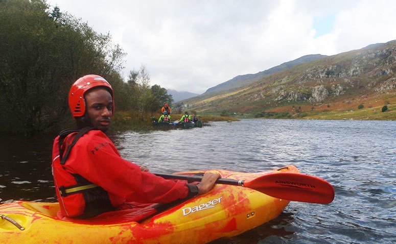 A student kayaking on a lake